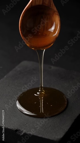 Pouring honey wooden spoon slate surface