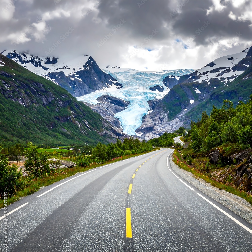 Fototapeta premium Asphalt road curves through lush green valley towards towering glacier and cloudy mountain peaks