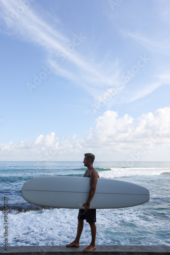 Beach Surfer Tranquility. Silhouetted Individual Walks Along Shoreline With Waves Crashing Nearby