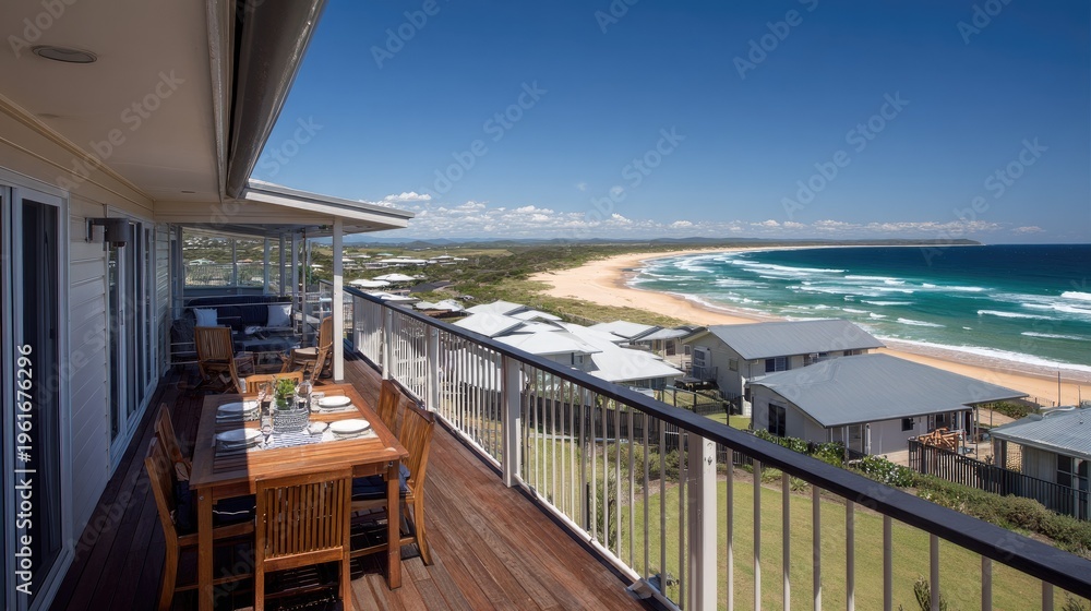 Fototapeta premium Elevated wooden deck overlooks expansive sandy beach and turquoise ocean water under clear blue sky