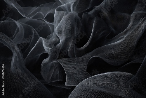 Close-up of flowing, sheer fabric with complex folds and shadows, in grayscale