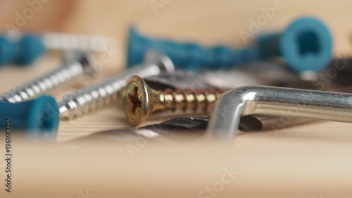 Macro view of assorted hardware including screws wall plugs and hex keys on wooden surface.