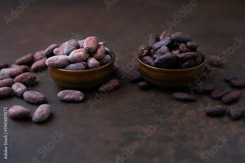 Cocoa beans and a pile of cocoa powder in wooden bowls on a stone table