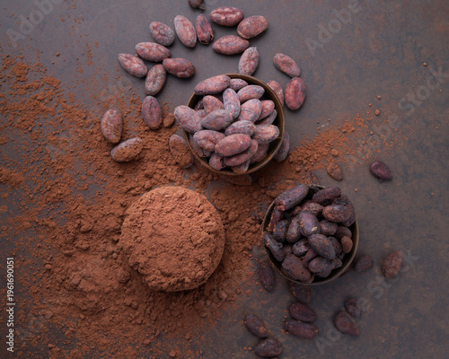 Cocoa beans and a pile of cocoa powder in wooden bowls on a stone table