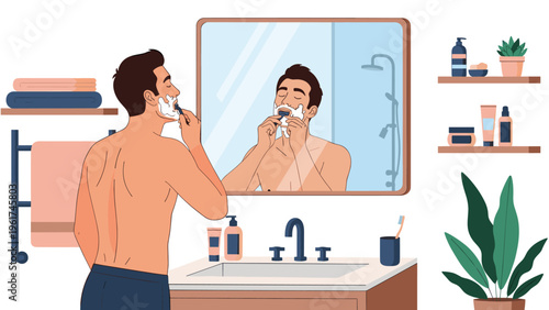 Young man shaving his face with razor in front of bathroom mirror while preparing for the day with grooming products on shelves nearby area.