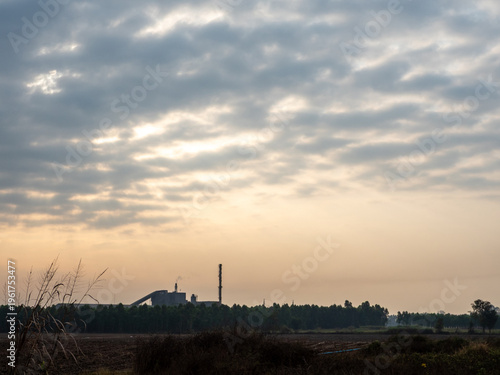 Factories and tall smokestacks stand alone amidst agricultural and wasteland areas