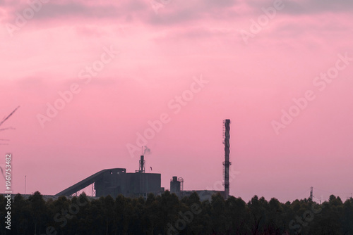 Factories and tall smokestacks stand alone amidst agricultural and wasteland areas
