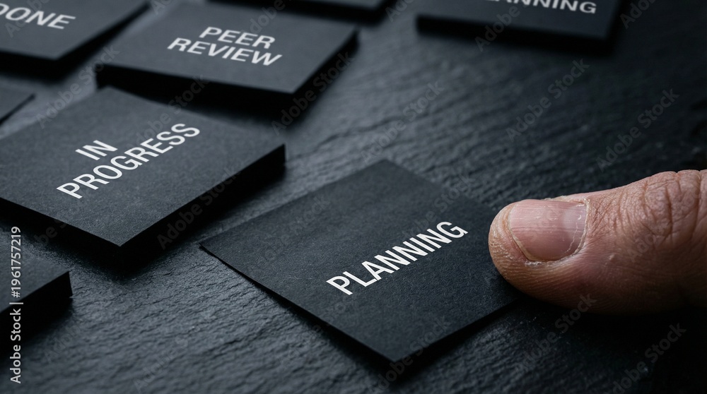 Fototapeta premium Strategizing Business Processes Hand Placing 'Planning' Tile on a Dark Textured Board Amidst Workflow Tasks