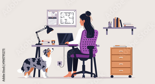 Woman sits working on computer with dog by her desk indoors
