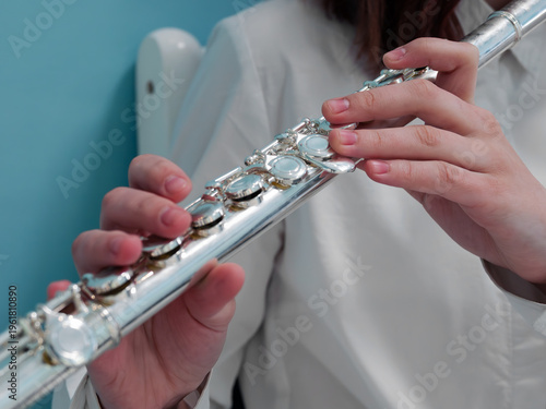 An unrecognizable Caucasian teenager playing the flute. Close-up