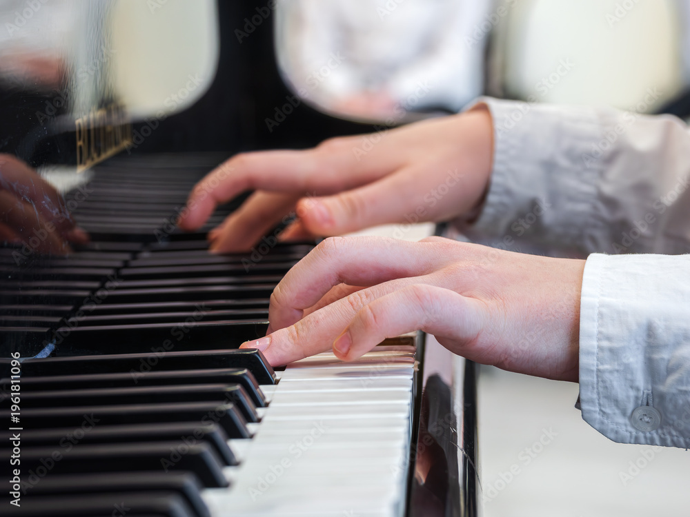 Fototapeta premium An unrecognizable Caucasian teenager playing the piano. Close-up