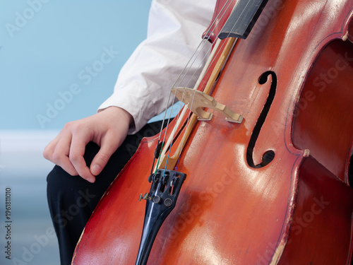 An unrecognizable Caucasian teenager playing the cello. Close-up