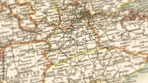 Tablou pe pânză Macro close up of a vintage map highlighting Surrey shire in England, showcasing detailed cartography, major towns, and classic antique textures ideal for travel, geography, and historical themes