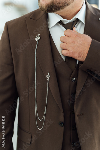 Groom Adjusting Brown Waistcoat and Suit Jacket During Wedding Preparations