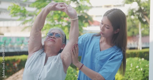 Physical therapist assisting an elderly woman with stretching exercises in a garden.