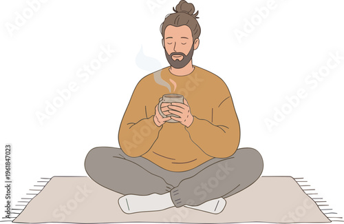 Man sitting cross-legged on a mat holding a steaming mug