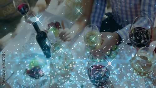 Diners prompted by shared meal reaching for glasses toasting at table, sparkle overlay on glasses