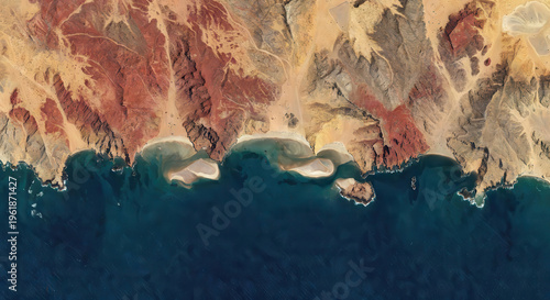Aerial view of a dramatic desert coastline meeting deep blue ocean waters with sandy inlet beaches