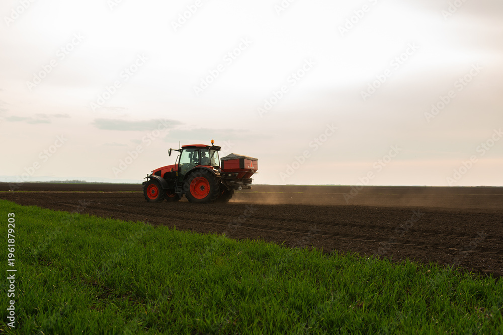 Fototapeta premium Tractor spreading artificial fertilizers in field