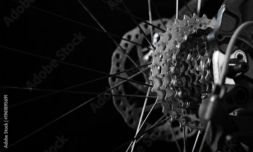 Close-up of bicycle rear cassette and chain with visible spokes on black background. Concept of cycling, sport, mechanical engineering, maintenance, repair and performance.