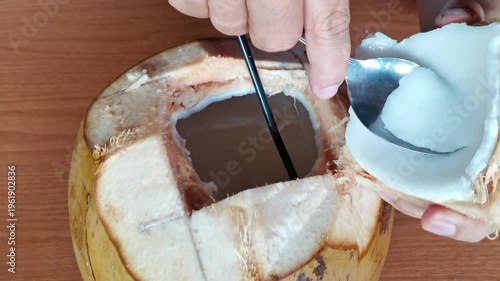 Fresh Young Coconut Being Scooped Out With a Spoon to Enjoy the Tender White Flesh and Water