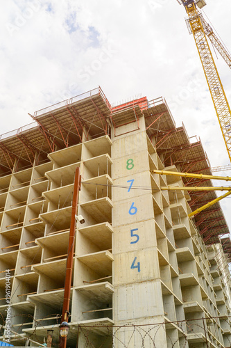 Construction of a multi-story concrete high rise building frame with tower crane machinery nearby.