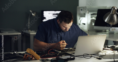 Tools, man and laptop repair in office for hardware diagnostics, measure voltage or troubleshooting. Night, technician and multimeter probe on circuit board for continuity test, broken traces and IT