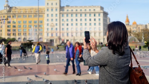 Canvas Print Traveling woman photographing barcelona city square, capturing historic building