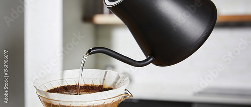 Person pouring hot water from kettle over ground coffee in filter. Preparation of drip coffee in kitchen. Morning ritual and lifestyle routine. Fresh caffeinated beverage brewing process.