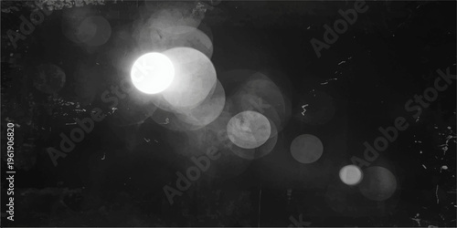 Glowing street lights reflect on a dark city road under a blue night sky filled with clouds and moonlight during a rainy evening in the city