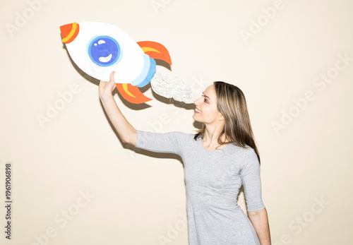 Woman holding handmade paper rocket symbolizing ambition and success