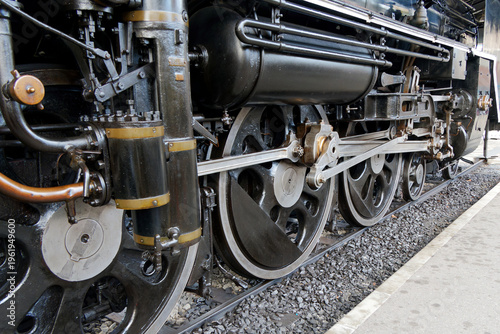 Detailed view of the large steel wheels and mechanical linkage of a vintage black steam locomotive.