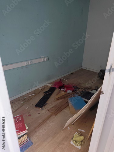 View of a messy empty room with debris, scattered wooden planks, and trash on the floor after a move or apartment eviction process.