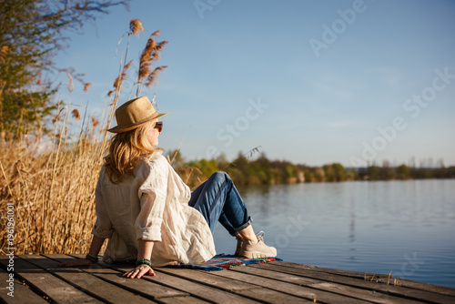 Woman relaxing on pier at lake. Tranquil solitude moment in nature, digital detox and mindful slow living