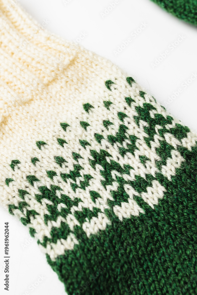 Fototapeta premium Close-up of a handmade knitted sock with green and white wool pattern.