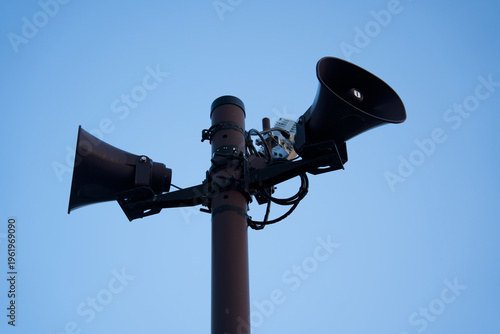 Картината върху платно Public address speakers on pole against blue sky