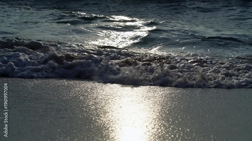 Close up of golden sunlight reflecting on ocean waves at Ko Libong beach in Trang, Thailand; Static real-time shot of shimmering Andaman Sea tide at sunset with sparkling water texture.