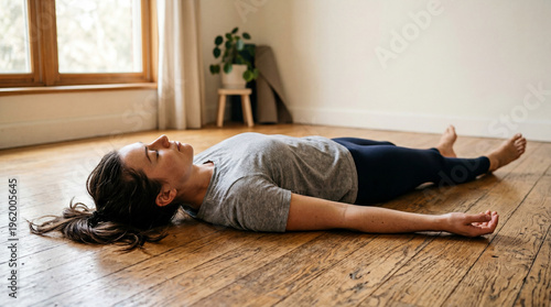 Embracing a profound stillness, a woman unwinds completely, finding serene solace on a sun-kissed floor in her tranquil living space
