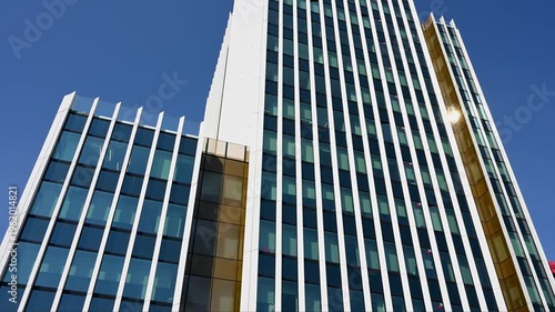 Modern glass building exterior with white pillars and blue sky