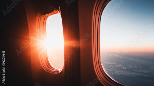 Airplane window capturing a warm sunset with glowing sunbeams, creating a serene and beautiful aerial view during travel