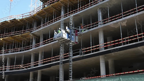 Building Construction with External Freight Lift and Workers