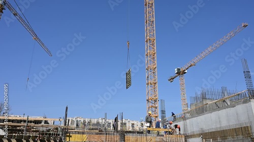 Tower Cranes Lifting Load at Busy Construction Site
