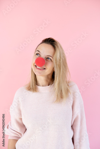 blond woman in front of pink background with red clown nose