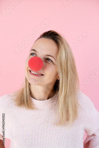 blond woman in front of pink background with red clown nose