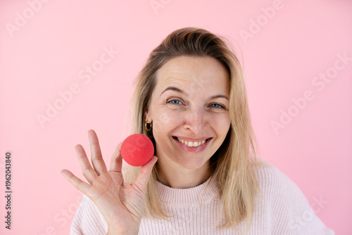blond woman in front of pink background with red clown nose