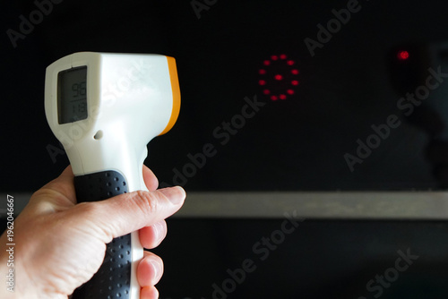 Hand using an infrared thermometer to measure the temperature of a black surface