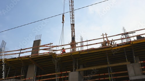Construction worker receiving cargo from crane at building site