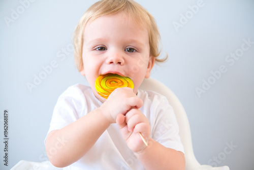 cute baby eating lollipop sitting in a baby chair. weaning