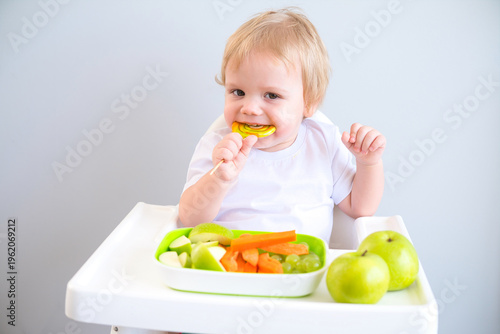 cute baby eating lollipop sitting in a baby chair. weaning