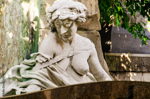 Female sculpture in white marble.The figure has part of her breasts exposed, a serene expression, and a downward gaze. Artist unknown, São João Batista Cemetery, RJ, Brazil.